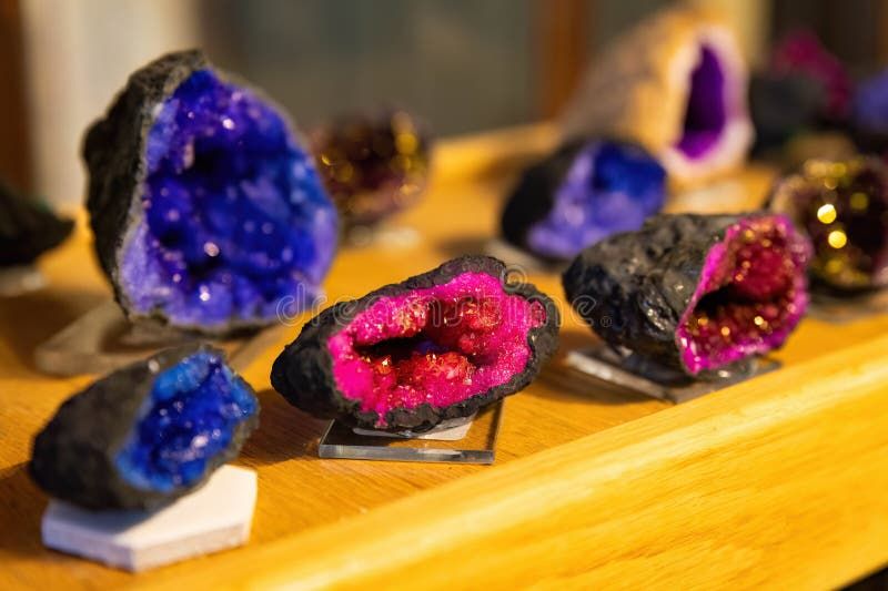 Färgglada geodeskivor med blå och rosa kristaller på en trähylla.